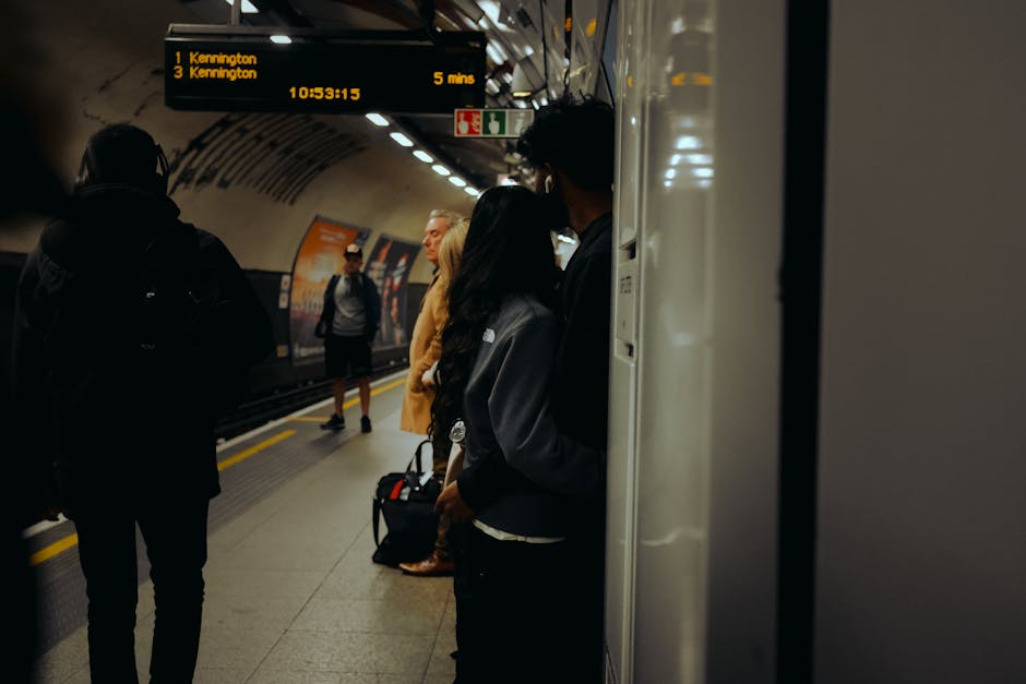A nighttime view of Kennington station platform, featuring train tracks running parallel to the platform edge, which is marked by a yellow safety line. The platform includes a textured tactile paving